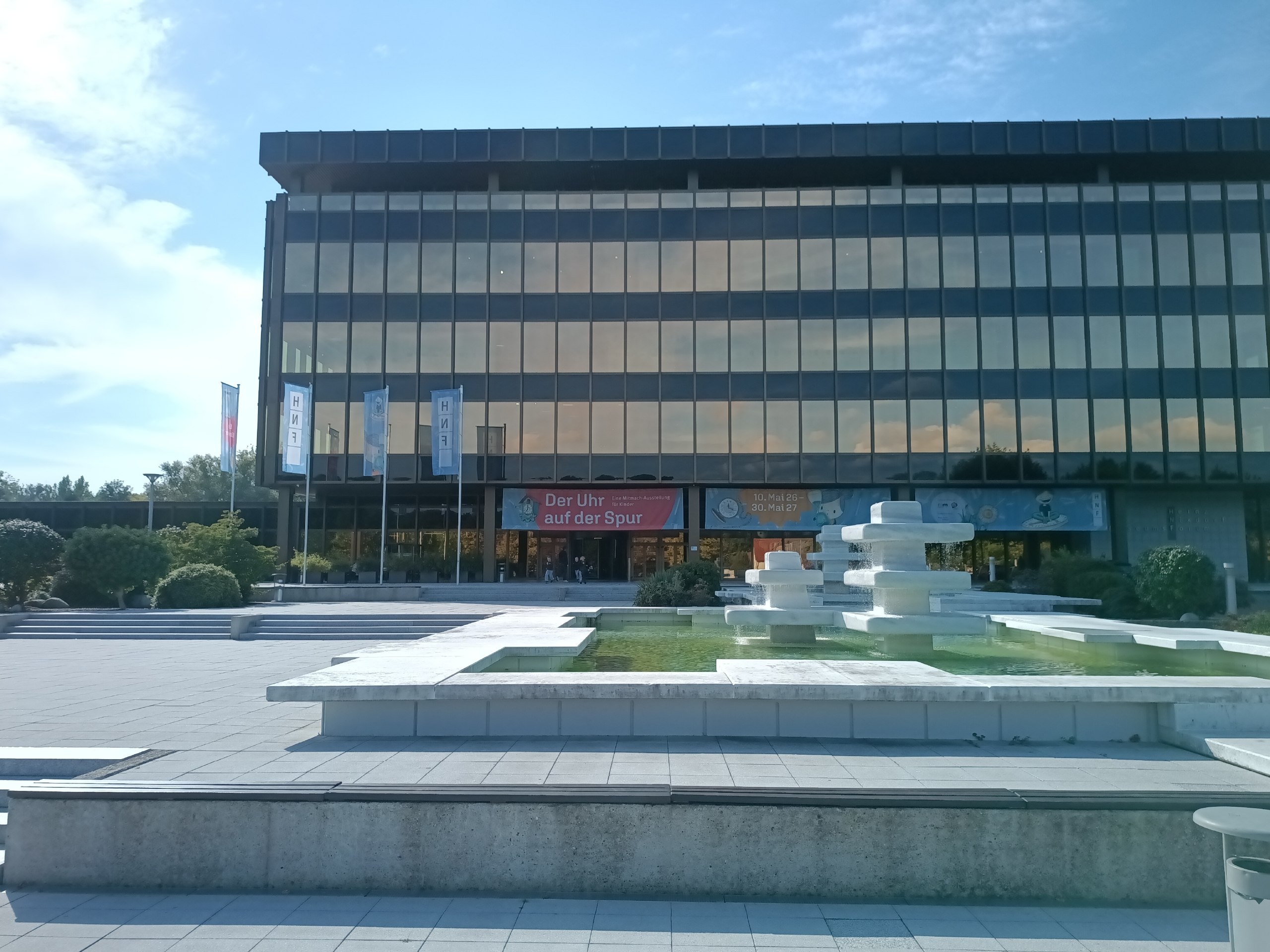 Die Front des Heinz Nixdorf MuseumsForums. Im Vordergrund ist ein weißer eckiger Brunnen zu sehen.