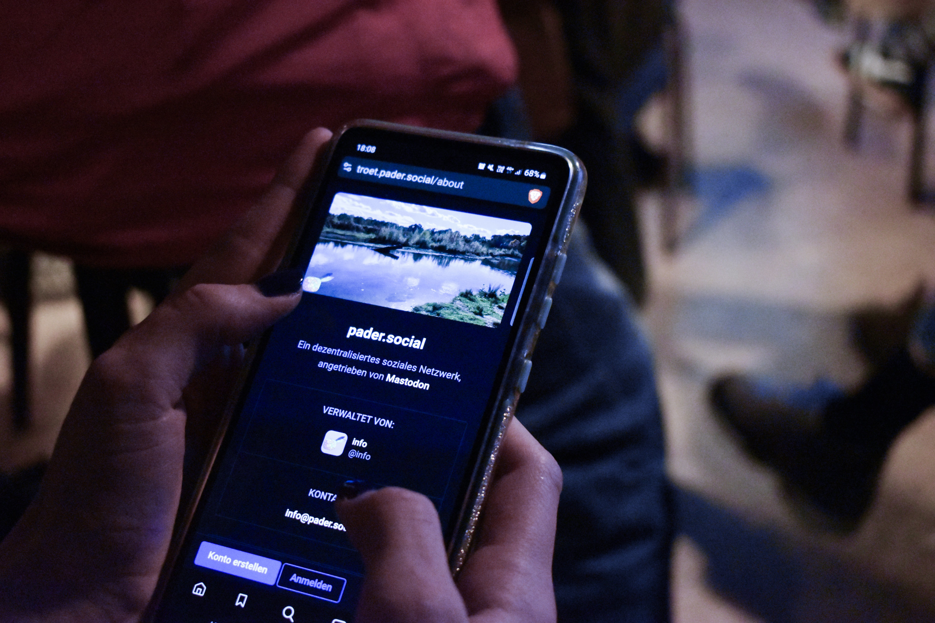 Telefon mit der Internetseite 'troet.pader.social/about\', die Seite zeigt das Mastodon-Profil von pader.social mit einem Titelbild vom Padersee und dem Text 'Ein dezentralisiertes soziales Netzwerk, angetrieben von Mastodon.'